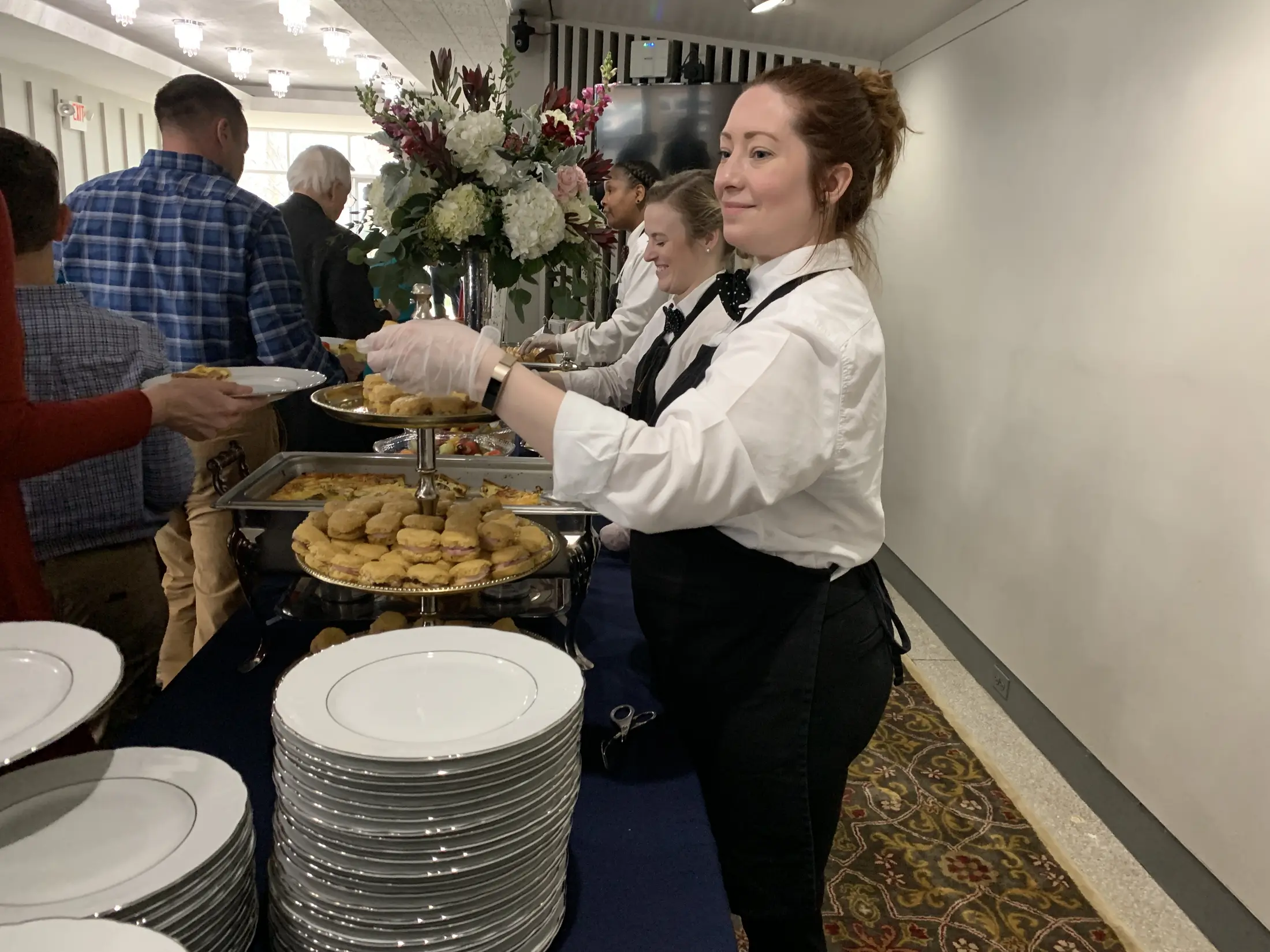 Catering staff serving guests at an interactive food station.